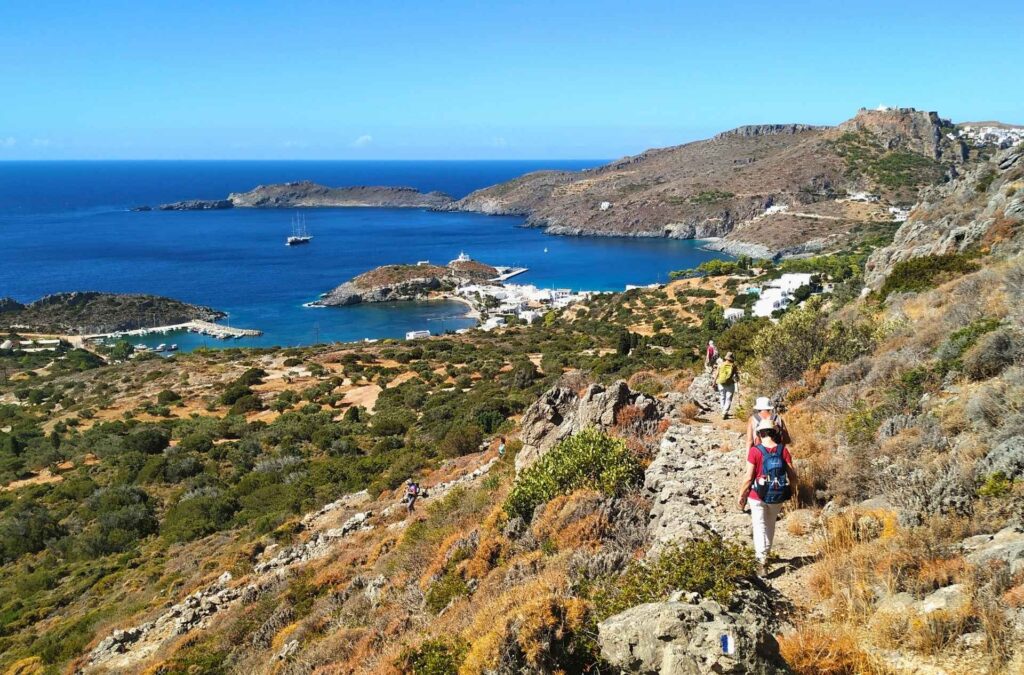 A hiker walking along a scenic cliffside trail overlooking the deep blue waters of Kythera.