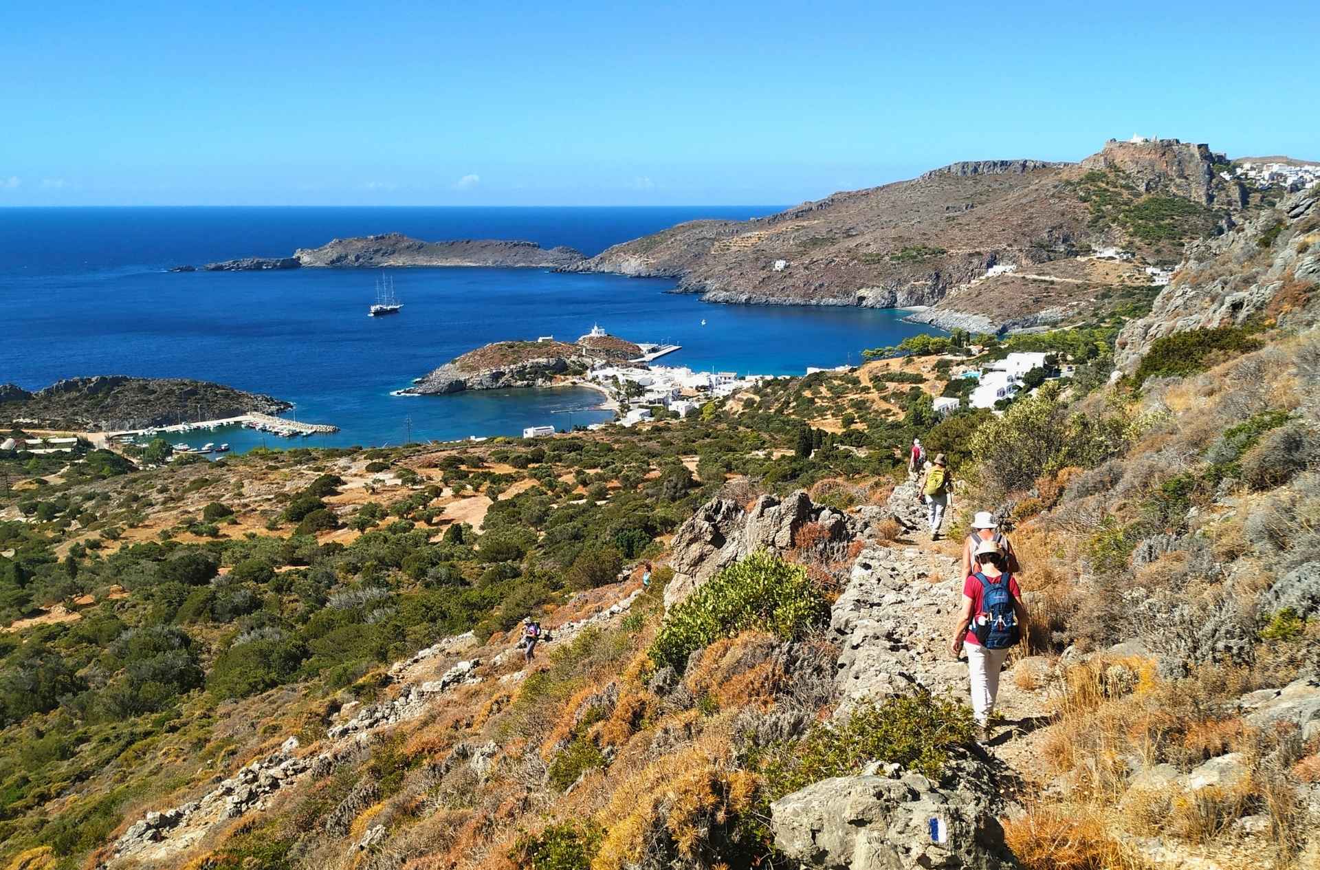A hiker walking along a scenic cliffside trail overlooking the deep blue waters of Kythera.