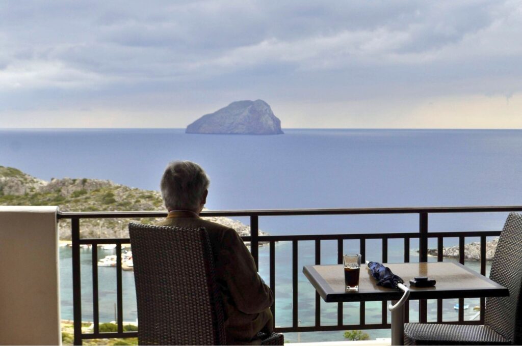 A traveler enjoying a quiet morning view from a balcony of an authentic Greek accommodation overlooking the sea in Kythera.