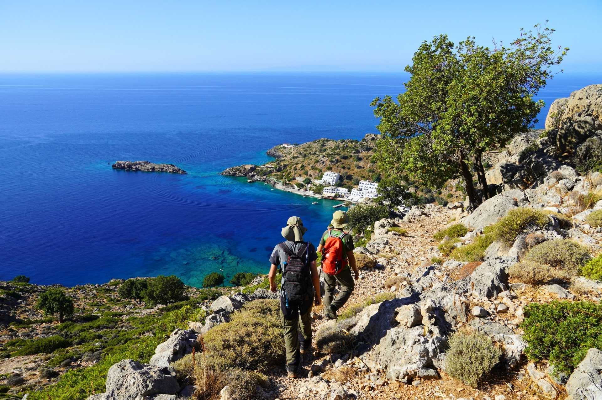 Coastal hiking trail in Greece with spring wildflowers and turquoise water.