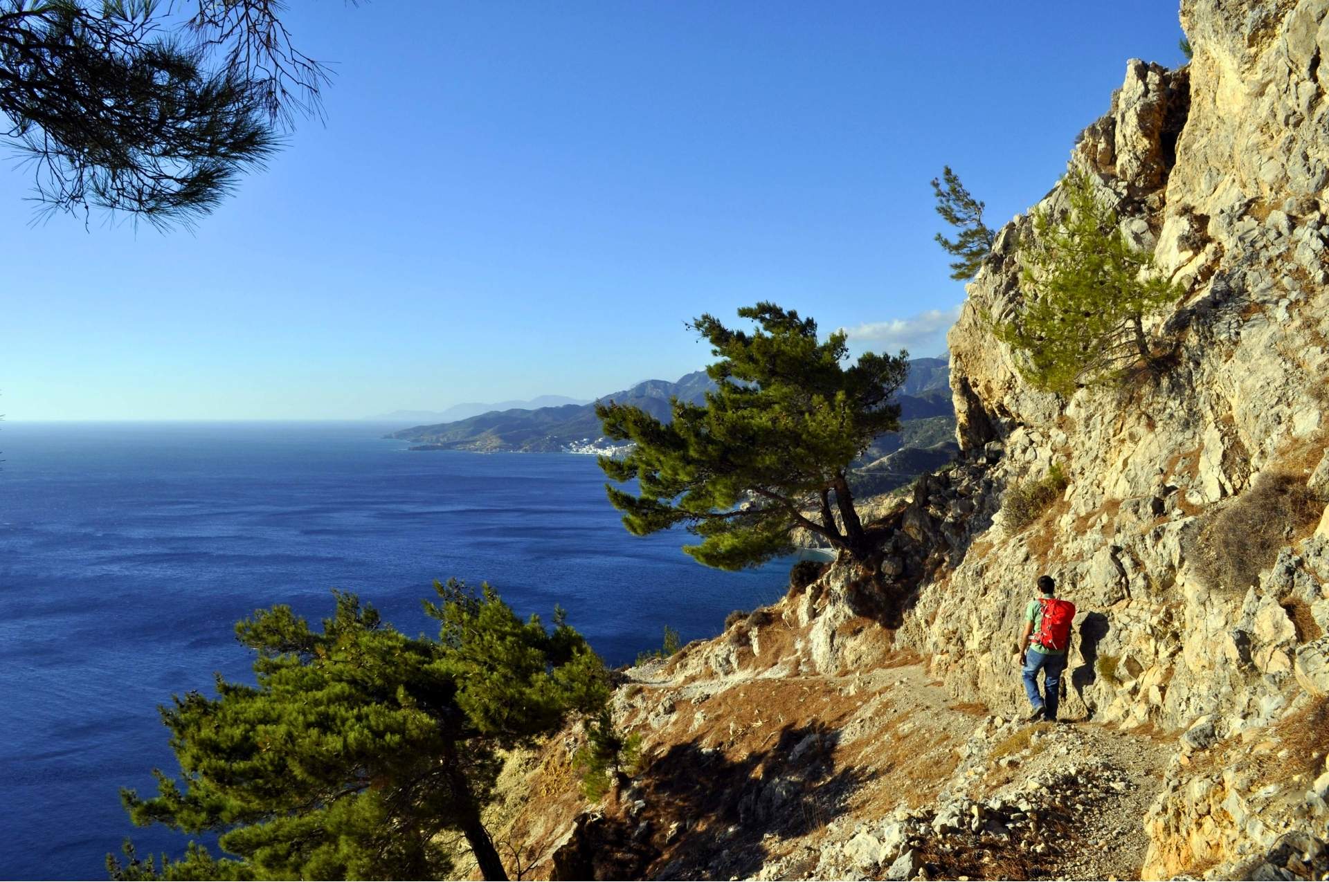 An exposed hiking trail along a cliffside in Karpathos overlooking the Aegean Sea.