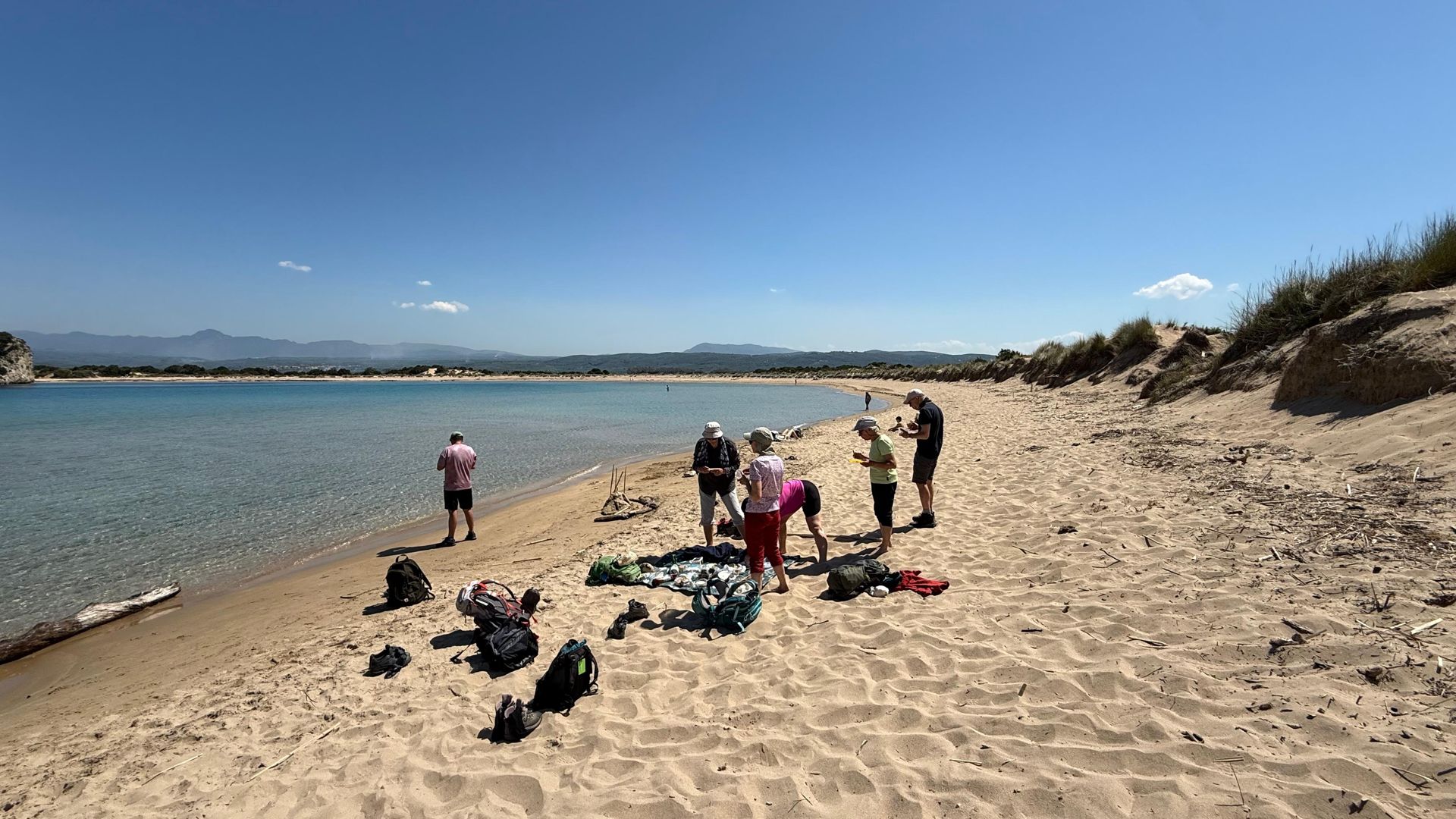 Hikers picnicking on a quiet sandy beach on the Peloponnese coast