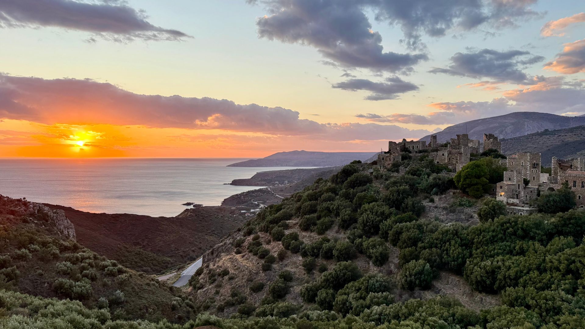 Sunset over the sea and a stone tower village on the Mani coast, Peloponnese